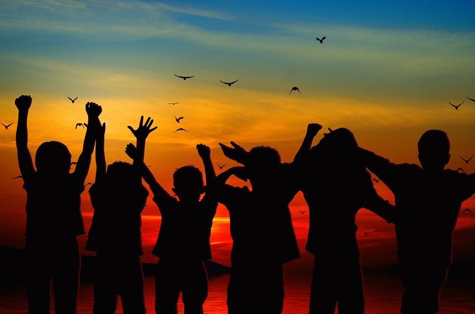 silhoutte at sunset of a group of people with their arms in the air