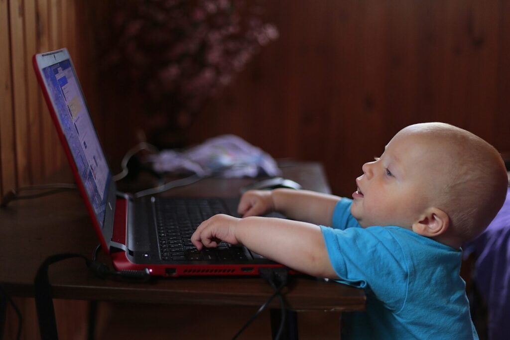 A baby plays on a laptop computer